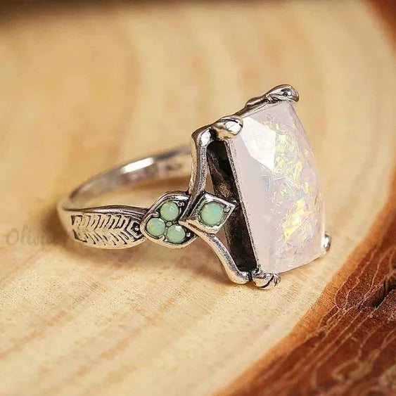 Vintage-Ring aus Silber mit weißem Opal, elegantes Design der Marke Rose & Oliver, präsentiert auf neutralem Hintergrund.