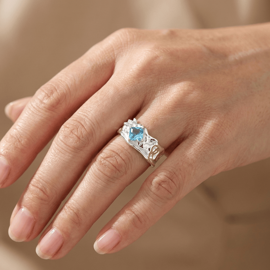 Anel ajustável de prata com textura e pedra de aquamarine, da marca Rose & Oliver, mostrado em detalhe.