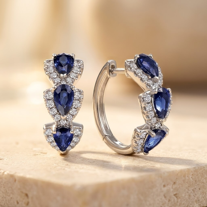 Brincos de argola prateados com halo de safira, da marca Rose & Oliver, detalhes brilhantes e elegantes.