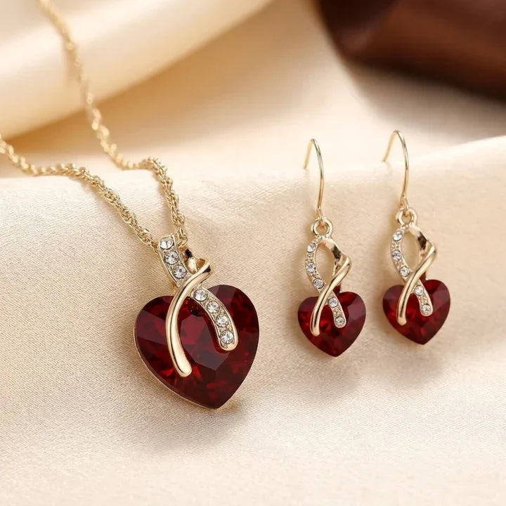 Rose & Oliver Schmuckset mit verdrehtem goldenen Herzen und roten Rubinen, einschließlich eleganter Halskette und Ohrringe für besondere Anlässe.