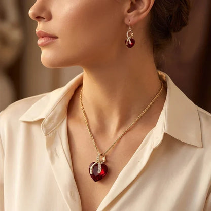Rose & Oliver Schmuckset mit gedrehtem Herz in Gold und Rubinen, inklusive Ohrstecker und zarter Halskette mit roten Steinen.