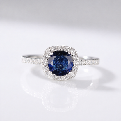 Anel de safira azul em corte cushion com halo de diamantes, produzido pela Rose & Oliver.
