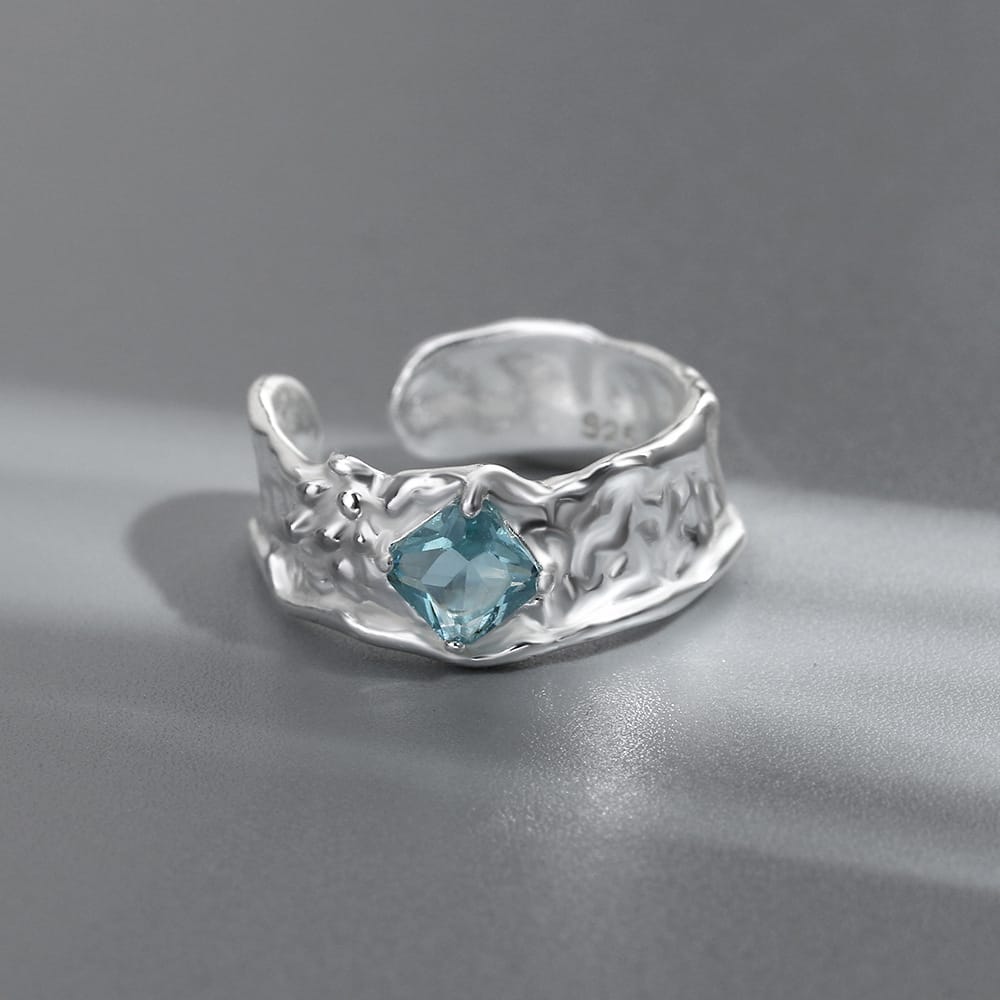 Anel ajustável Rose & Oliver com textura prateada e pedra de aquamarina brilhante, exibido em close.