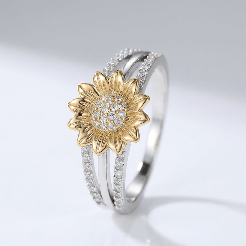 Anel de prata e ouro com design de girassol e diamantes, da marca Rose & Oliver, destacando detalhes brilhantes e delicados.
