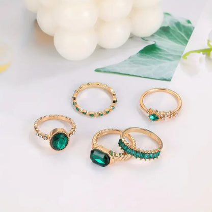 Conjunto de joias Zarina com anéis de esmeralda e ouro, design elegante da marca Rose & Oliver, detalhes em pedras preciosas.